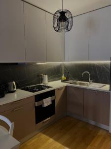 cocina con armarios blancos, fogones y fregadero en Maestral Living Studio Apartment, en Zagreb