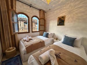 Dos camas en una habitación con dos ventanas. en Maison traditionnelle totalement privée au médina, en Chefchaouen