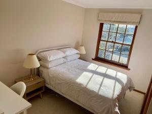 a bedroom with a white bed and a window at Hillside Retreat with Pool in Flagstaff Hill