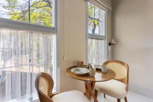 a dining room with a table and chairs and a window at Vilinha típica - Suíte Onze Tuin - Entrada com senha - Somos hospedagem por temporada in Holambra