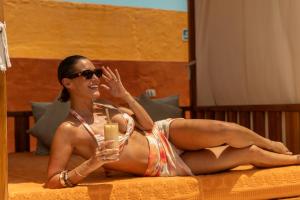 a woman in a bikini laying on a bed with a drink at Casa Carolina Luxury Wellness Hotel in Cartagena de Indias