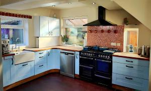 a kitchen with white cabinets and a black stove top oven at Durham Hot Tub - Steam Spa - Eco Retreat - Pizza Oven - Log Burner - Pets Ok - Garden in Langley Park
