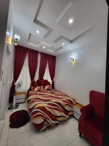 a bedroom with a large bed and a red chair at Trinity Apartments in Lagos