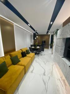 - un salon avec un canapé jaune et une cheminée dans l'établissement Arad Apartamente Premium, à Arad