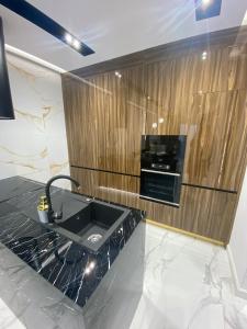 - une cuisine avec un évier noir et un mur en bois dans l'établissement Arad Apartamente Premium, à Arad