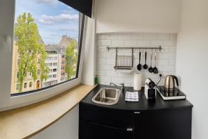 a kitchen with a sink and a large window at Apartments KR in Cologne
