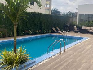 ein Swimmingpool mit einer Palme in einem Hof in der Unterkunft Belrose Place in Accra