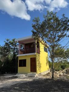 a yellow house with a balcony and a tree at Casa en Huerto Frutal in Chicanna