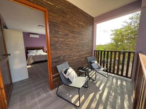 a room with two chairs and a balcony with a bed at Casa en Huerto Frutal in Chicanna