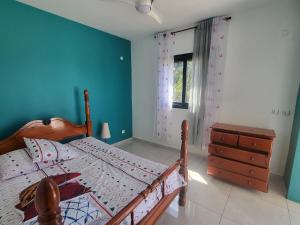 a bedroom with a bed and a dresser and a window at Chambre indépendante calme pour femmes, en forêt, 1km plage in Deshaies