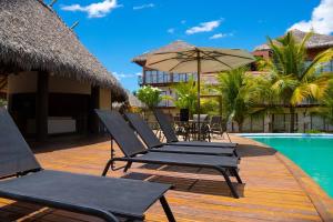 a deck with chairs and an umbrella next to a pool at Villas BobZ Barra grande in Barrinha
