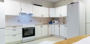 a white kitchen with white cabinets and appliances at Senja Fjord Lodge in Senja