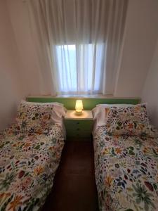 zwei Betten in einem kleinen Zimmer mit Fenster in der Unterkunft Mi Pequeño Paraíso in El Pris