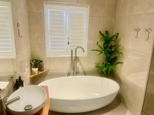 a white bath tub in a bathroom with a plant at Voir la Mer - Grotto Bay in Grotto Bay +28 photos
