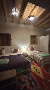 a bedroom with two beds and a rug on the floor at LA HACIENDA Agafay Desert  +46 photos