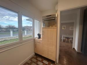 a kitchen with a large window and a view of a field at Maison chaleureuse à 2 minutes de la mer in Colleville-Montgomery