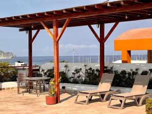 a patio with chairs and a table and a view of the ocean at Luxury Boutique Apartments by Xarm Apartments in Santa Marta