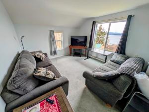 a living room with two couches and a television at Alert Bay, Spacious Executive Suite with Panoramic Ocean Views in Alert Bay