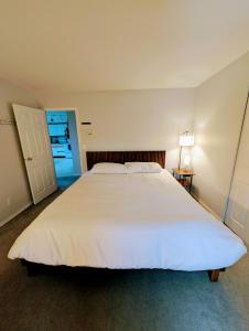 a large white bed in a bedroom with a lamp at Alert Bay, Spacious Executive Suite with Panoramic Ocean Views in Alert Bay