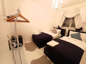 a bedroom with two beds and a chandelier at Luxury 3 Bedroom House with Parking in Northfleet +13 photos