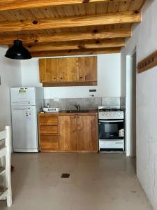a kitchen with wooden cabinets and a white refrigerator at Chalten Mountain Loft 6 in El Chalten