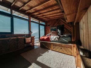 a bedroom with a bed in a room with windows at Lake Atitlán Panorama Chalets in San Marcos La Laguna