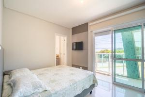 a bedroom with a bed and a large window at Apartamento vista para o mar com 02 dormitórios in Canto Grande
