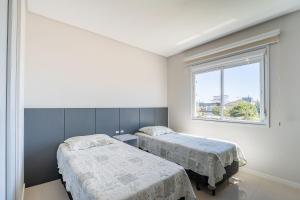 two beds in a white room with a window at Apartamento vista para o mar com 02 dormitórios in Canto Grande