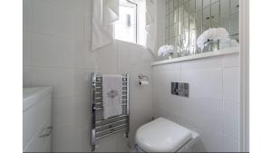 a white bathroom with a toilet and a window at Luxury 3 Bedroom House with Parking in Northfleet