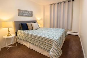 a bedroom with a bed with a striped blanket and a window at 2BR Downtown apt Amazing View Free Parking & Gym in Saskatoon