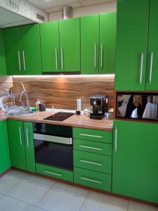 a green kitchen with green cabinets and a microwave at Луксозен апартамент in Vratsa
