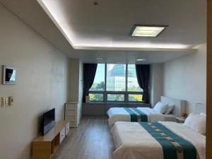仁川市温馨小屋Cozy House的有两张床和一台电视的酒店房间