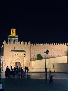a large white building with a clock tower at night at M & S Guest House in Fès