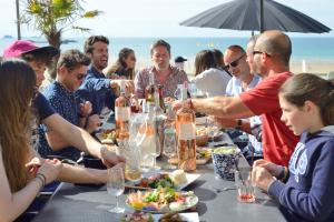een groep mensen die rond een tafel aan het strand zitten bij Les Charmettes in Saint-Malo