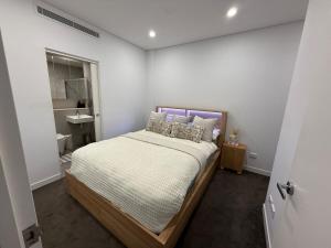 a bedroom with a bed and a bathroom with a sink at The Gosford Modern Nest in Gosford