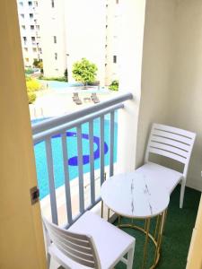 a balcony with two chairs and a table and a pool at Cozy 2BR Seawind Near Airport and Samal Island in Davao City +14 photos