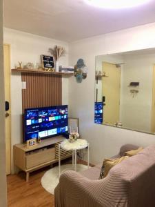 a living room with a large television and a mirror at Cozy 2BR Seawind Near Airport and Samal Island in Davao City