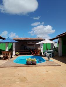 a swimming pool with two potted plants and an umbrella at Pousada Villa Zarah in São Miguel do Gostoso