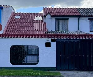 ein weißes Haus mit einem Tor und einem roten Dach in der Unterkunft La Casa in Bogotá