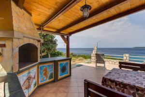 an outdoor patio with a stone fireplace and the ocean at House Nevenka in Štivan