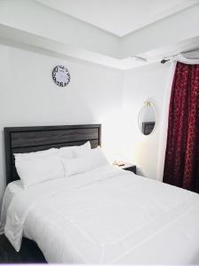 a bedroom with a white bed and a clock on the wall at Home away from home in Elizabeth