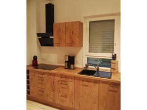 Una cocina con armarios de madera y un fregadero y una ventana. en Moderne Ferienwohnung mit Sauna & Terrasse, en Burhave 5 fotos más