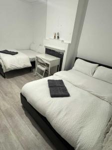 ein Schlafzimmer mit zwei Betten und einem Tisch und einem Stuhl in der Unterkunft Comfort rooms near City Airport in London