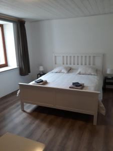 un grand lit blanc dans une chambre avec parquet dans l'établissement La ferme de la Semois au bord de l'eau, à Laviot