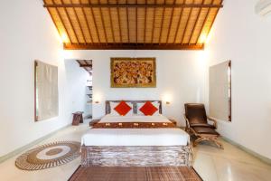 a bedroom with a large bed and a chair at Villa Tegal Tis Ubud in Payangan