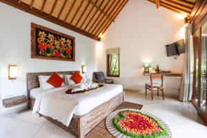 a bedroom with a bed and a table with flowers on it at Villa Tegal Tis Ubud in Payangan