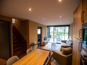 a living room with a wooden table and a staircase at Mountain-view eco-friendly cottage in Marcoux