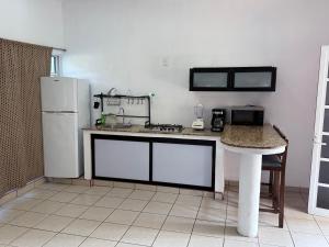 a kitchen with a white refrigerator and a table at Hotel y Bungalows Bugambilias in San Patricio Melaque