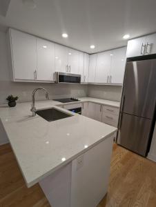 eine Küche mit weißen Schränken und einem Edelstahlkühlschrank in der Unterkunft Modern Condo in Ottawa Downtown in Ottawa