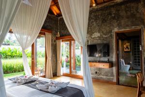 a bedroom with a bed with white drapes at Asiki Villa Sebatu in Tegalalang